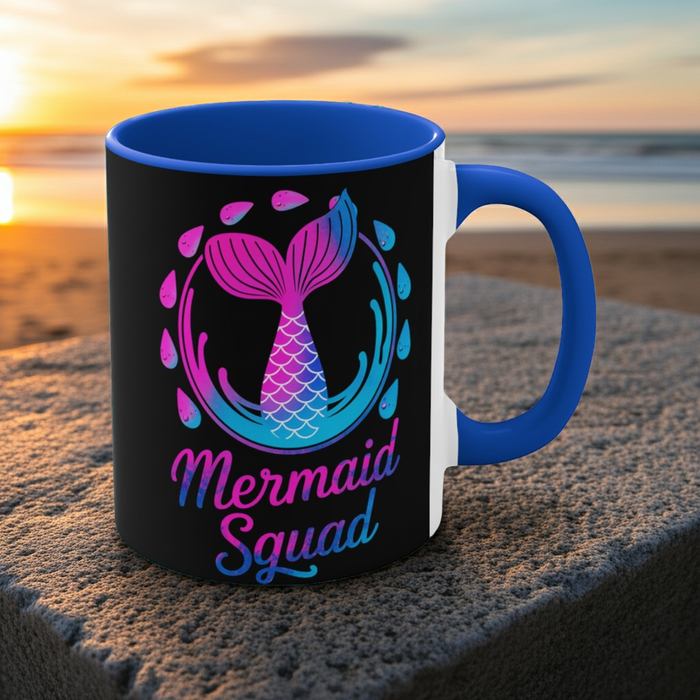 Blue-handled black ceramic mug with mermaid squad graphic, pink and teal scales.