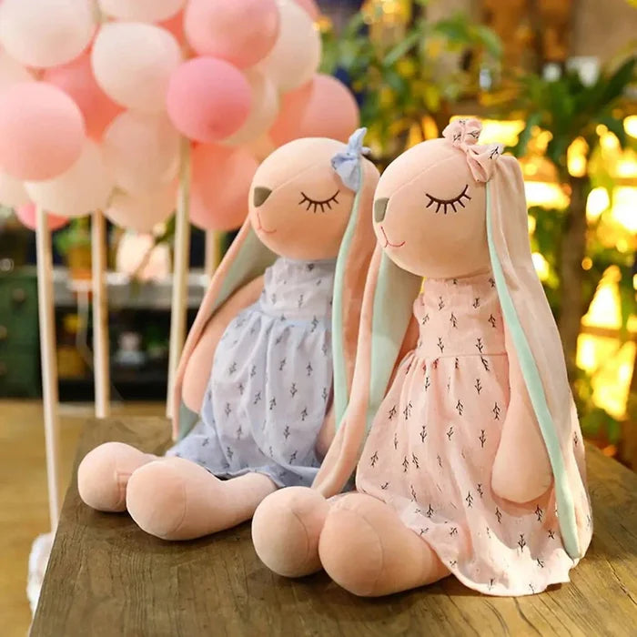 Two sleeping rabbit plush toys: pink and blue with mint-green ears and cactus-pattern dresses