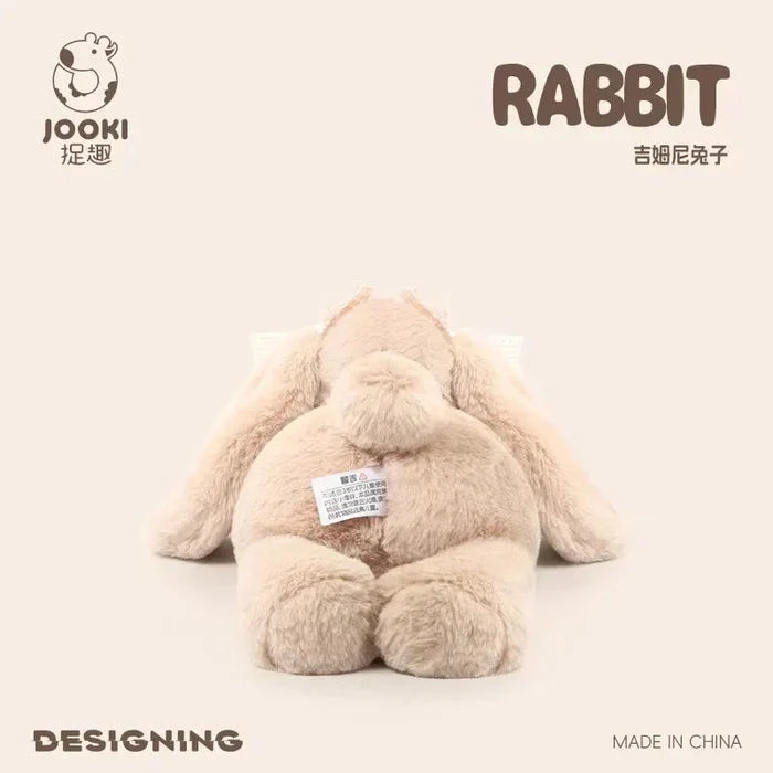 Beige plush rabbit toy, sitting pose, small white fabric tag on belly.