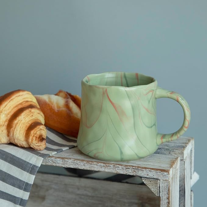 Mint green ceramic coffee mug with abstract red and white swirls, right-side handle