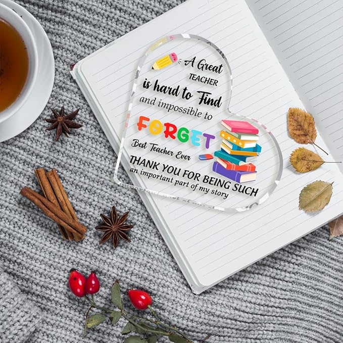 Clear acrylic heart plaque with teacher quote on an open notebook, books stack illustration