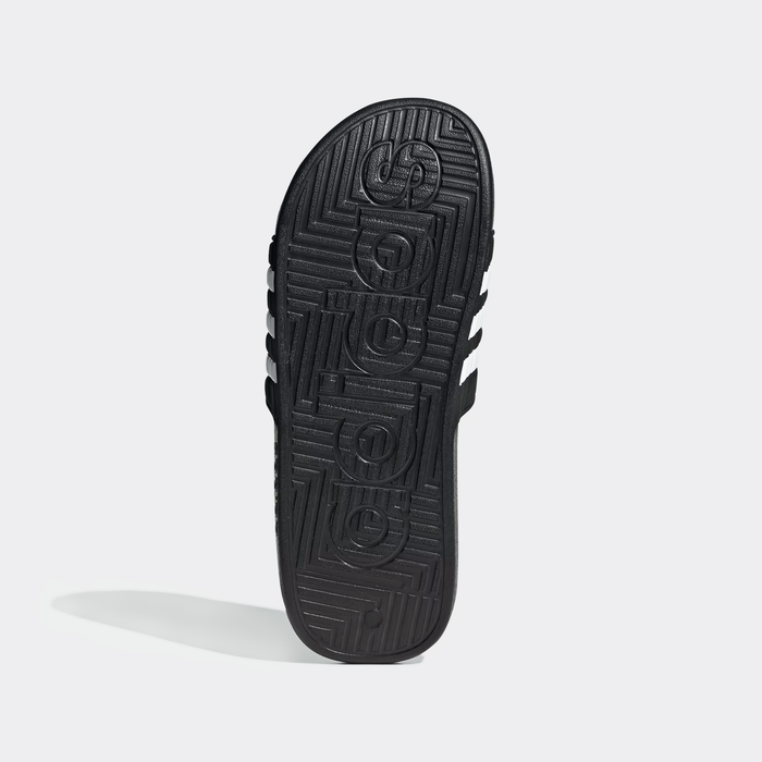 Adidas Adissage Slide sandal sole view showing textured black rubber outsole with Adidas logo and geometric pattern.
