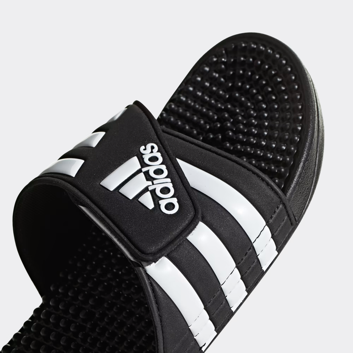 Adidas Adissage Slide sandals in black with white stripes, featuring adjustable strap and textured footbed, angled close-up view.