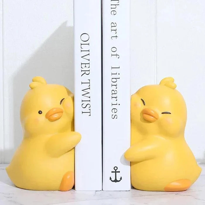 Yellow duck book ends, set of two, displayed beside a book spine