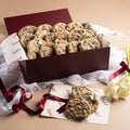 Oatmeal raisin cookies in a brown gift box with tissue paper and ribbon