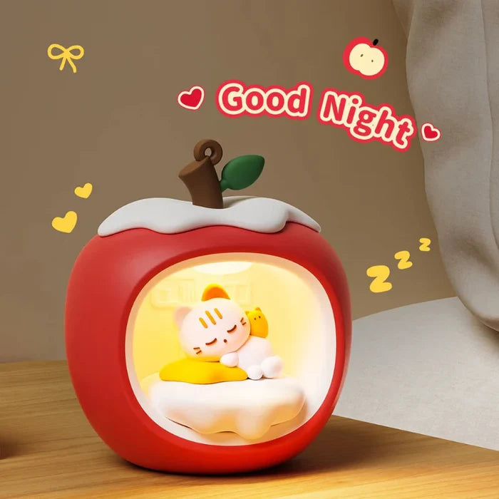Apple-shaped cat nap night light with glowing round window, red body and white cloud top.