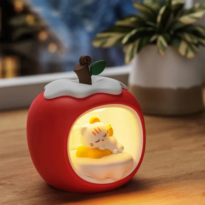 Apple cat nap night light on table with warm glow, red body and white cloud cover.