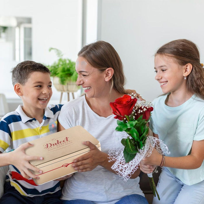 Family holding Dulcet scone gift tins and bouquet of flowers, smiling together