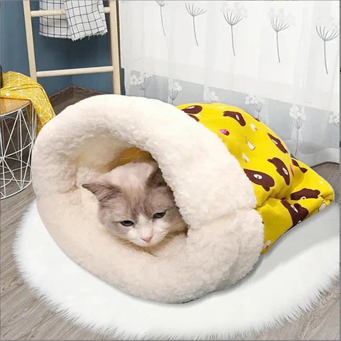 Closed cat sleeping bag with plush hood and yellow bear-print cover; cat inside