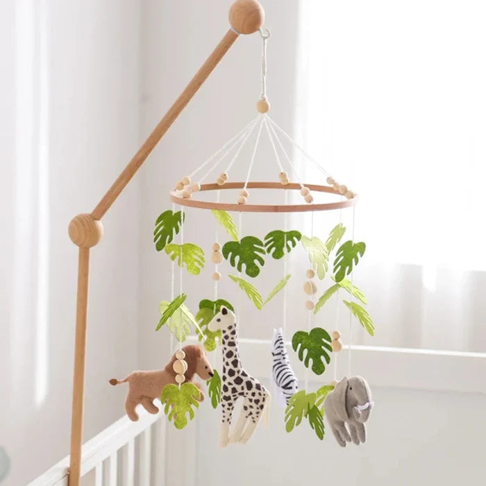 Wooden crib mobile with forest animal plushes, green leaves, and hanging bell toys