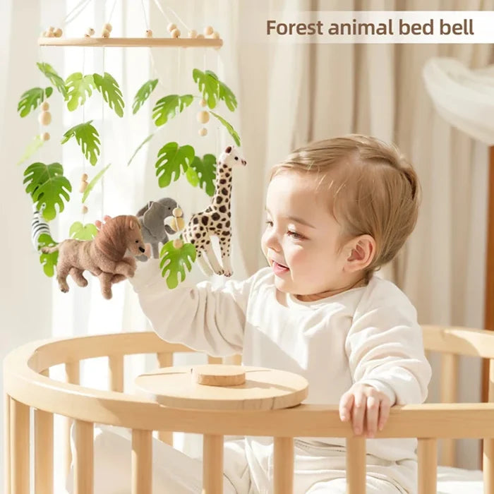 Baby playing with a forest animal crib mobile featuring hanging plush leaves and animals