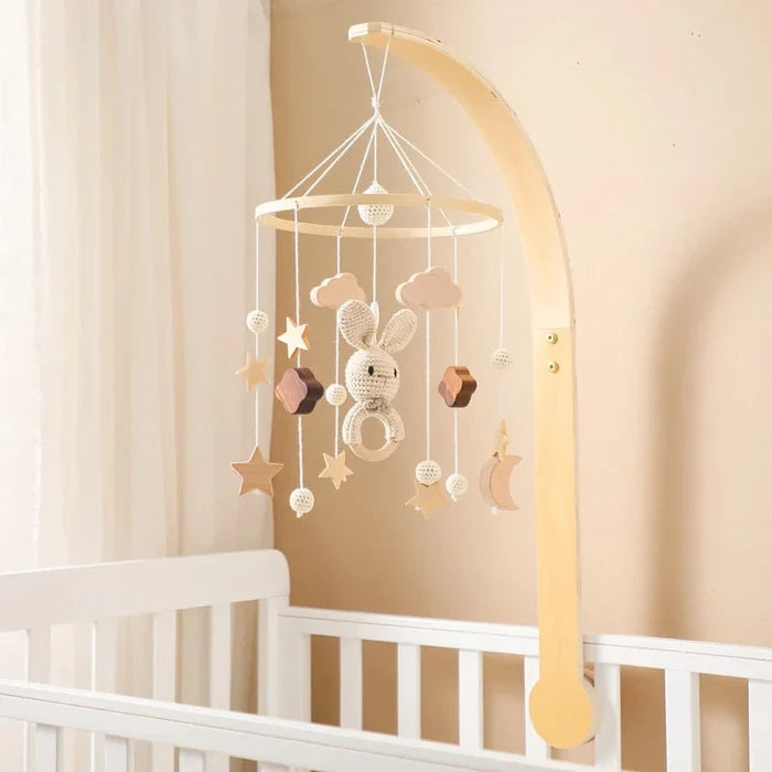 Baby bed bell mobile with crochet rabbit and star ornaments hanging from wooden arc frame