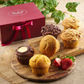 Assorted muffins on a wooden board with a maroon gift box and bow