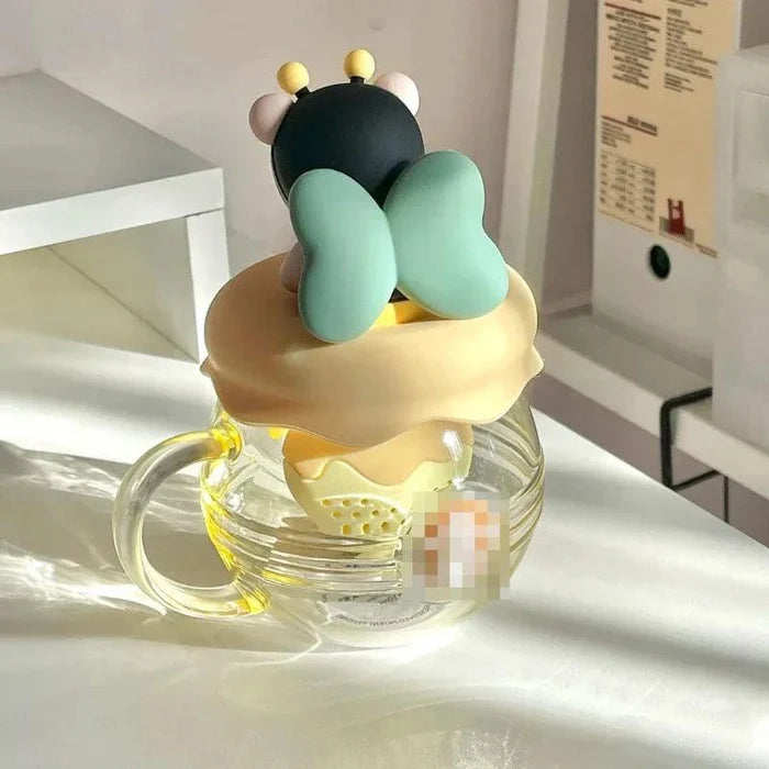 Glass tea infuser mug with bear character topper, mint arms, and honey-yellow lid