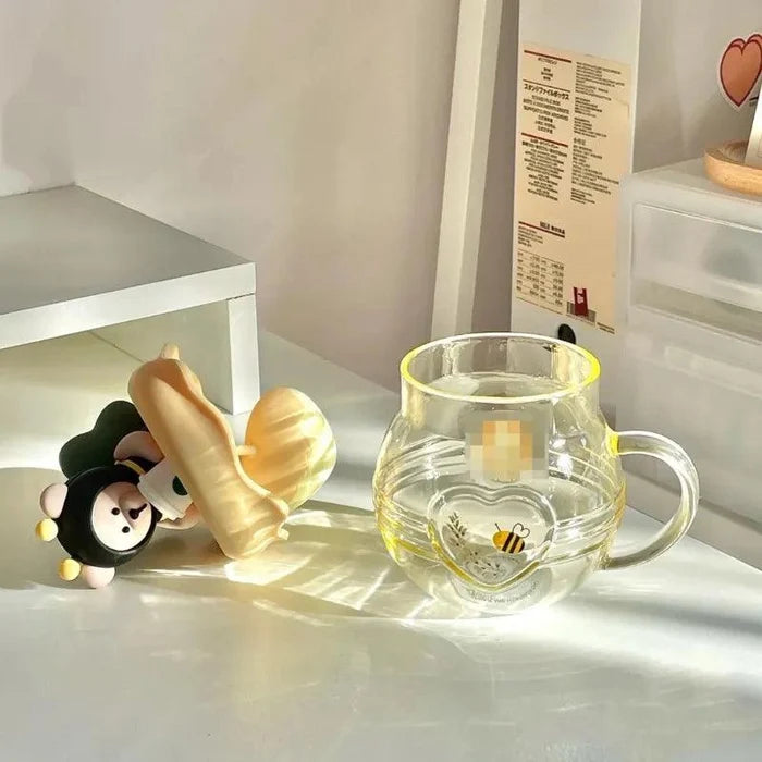 Glass tea infuser mug with bear topper and honey-yellow lid, clear handle on side