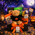Halloween treats gift basket with plush bear, orange ribbon, and assorted candy bags