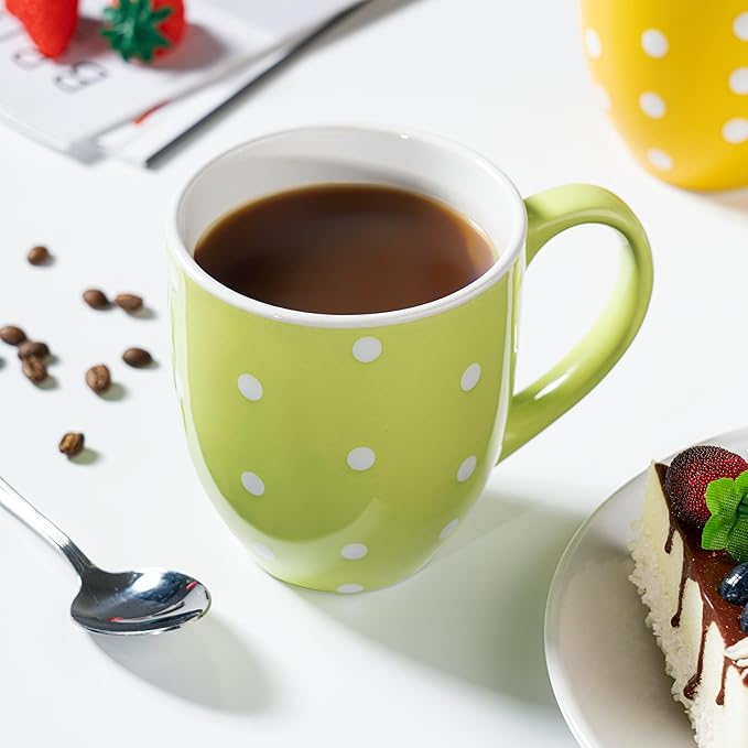 Green ceramic coffee mug with white polka dots and curved handle, filled with dark coffee.