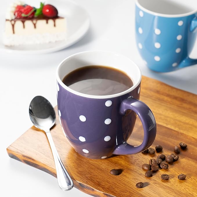 Purple ceramic coffee mug with white polka dots and handle, on wooden board with coffee.