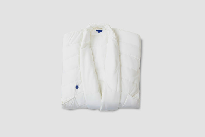 A folded, white Blanket Robe with a small blue button detail on the front, displayed against a solid light background