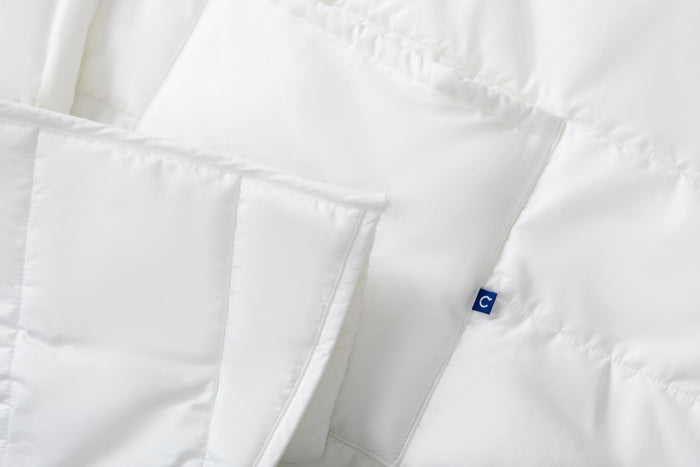 Close-up of a white Blanket Robe showing the fabric texture, stitching, and a small blue, square, Casper logo tag