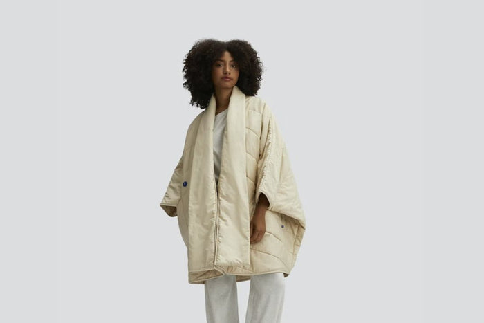 A person wearing the Snoozewear Blanket Robe, oatmilk