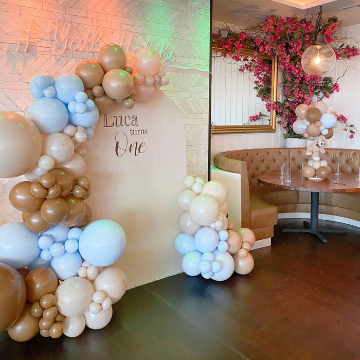 Balloon garland backdrop with cream, gold, and light-blue balloon clusters
