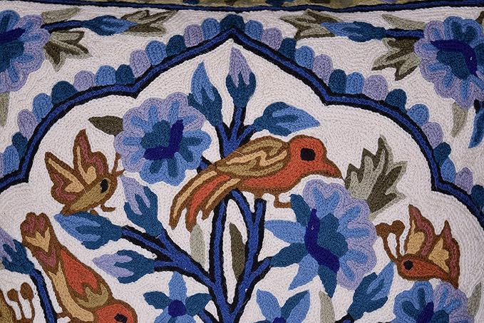 Blue floral pillow cover corner detail with bird embroidery and dark blue stitched border.