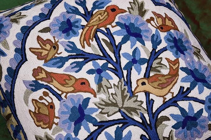 Embroidered bird and flower motif on blue floral pillow cover with dark blue outline.