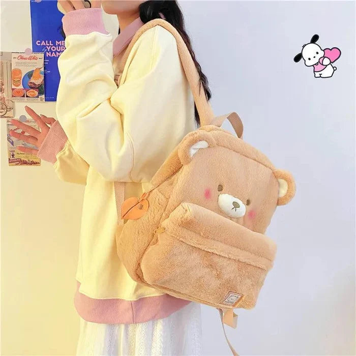 Light tan plush bear backpack worn over one shoulder, showing bear face and front pocket