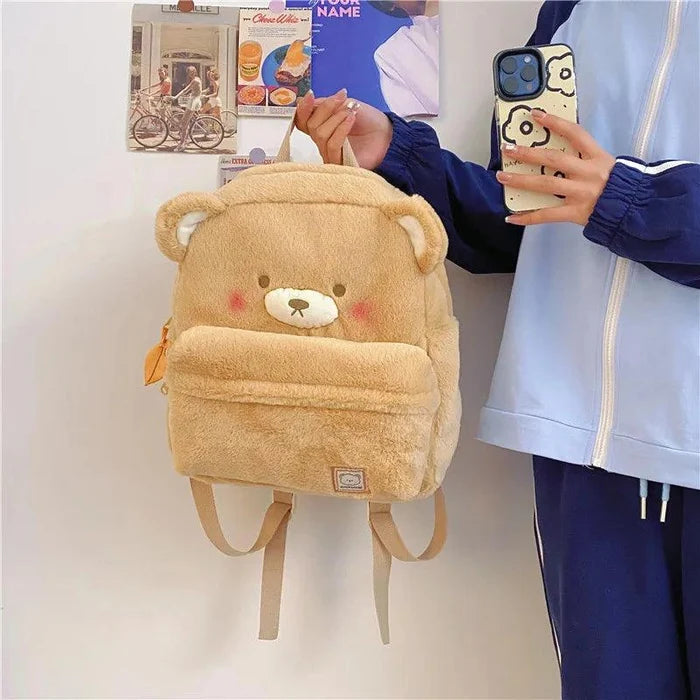 Light tan plush bear backpack front view with bear face patch and dangling bottom straps