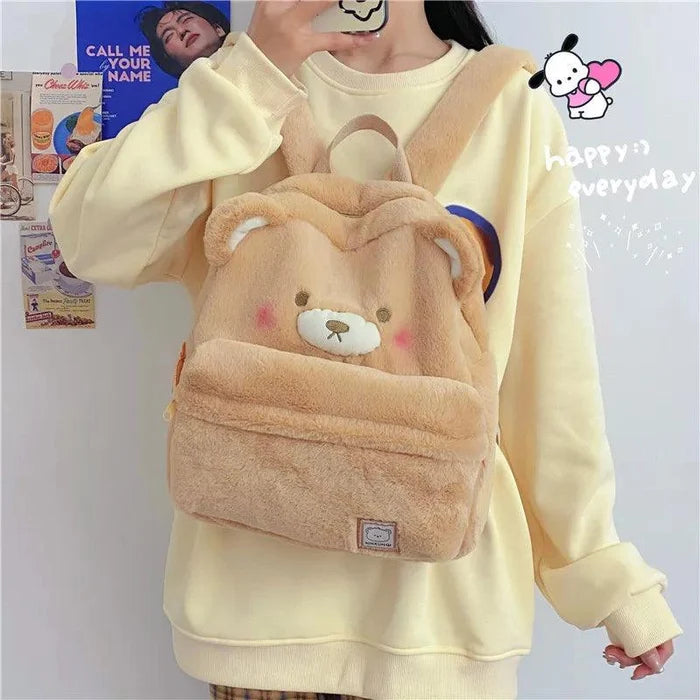 Light tan plush bear backpack on a person, bear face patch centered on the front flap