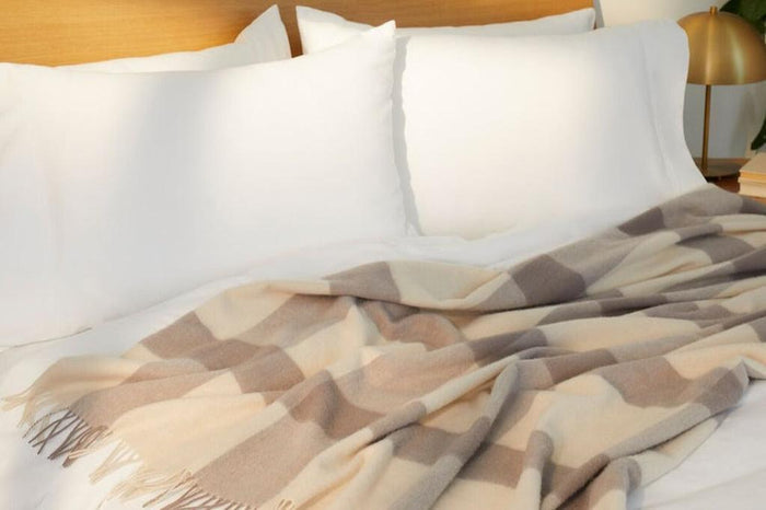 Bold Plaid Throw blanket, oatmilk, on a bed