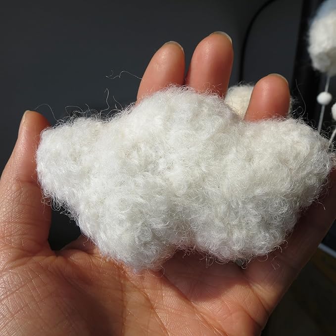 White plush moon charm for crib mobile, fuzzy texture shown in hand