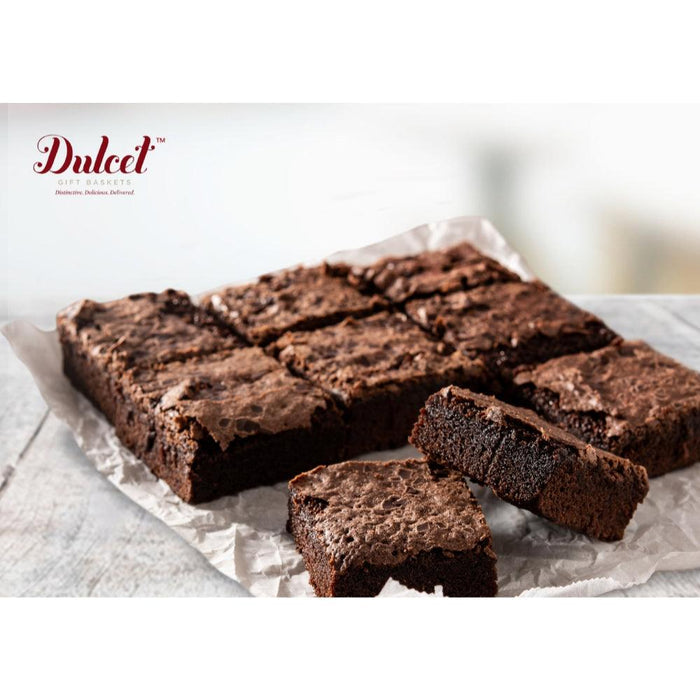 Chocolate brownie slab with cut squares and crumbs on parchment paper
