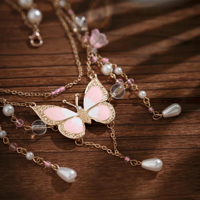 Gold multi-layer necklace with pink butterfly, faux pearls, and dangling drop charms