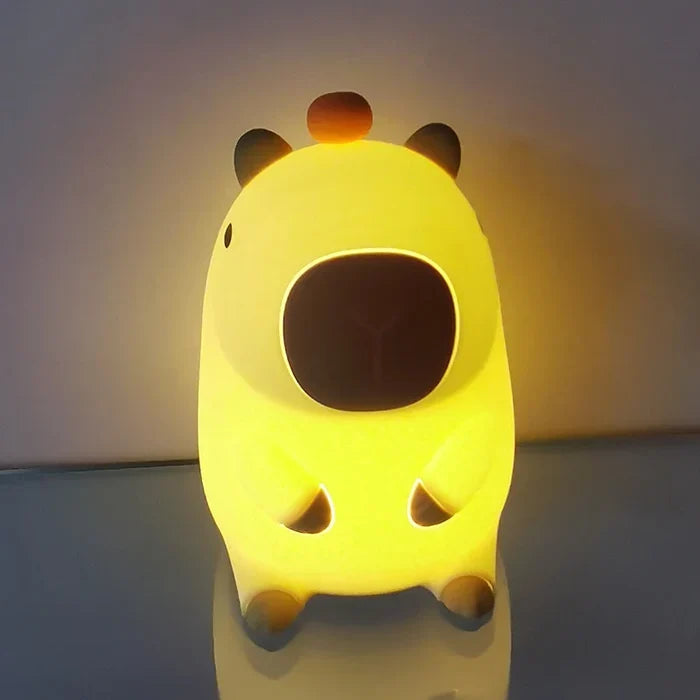 Yellow-lit capybara night light front view with rounded ears and orange top