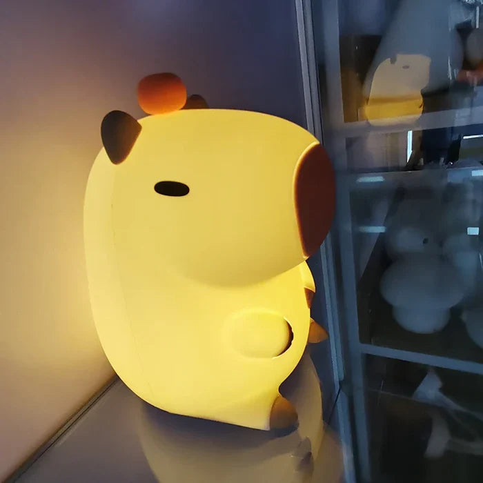 Capybara night light glowing on a floor with shelving in the background