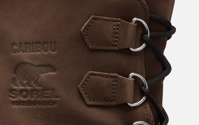 Sorel Caribou Winter Boots close-up of brown leather upper with embossed branding and waterproof detail, featuring durable metal eyelets and black laces.