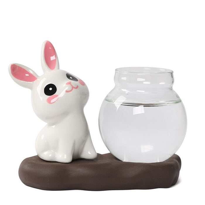 Ceramic bunny planter with clear glass vase, green leaves not visible, on dark base