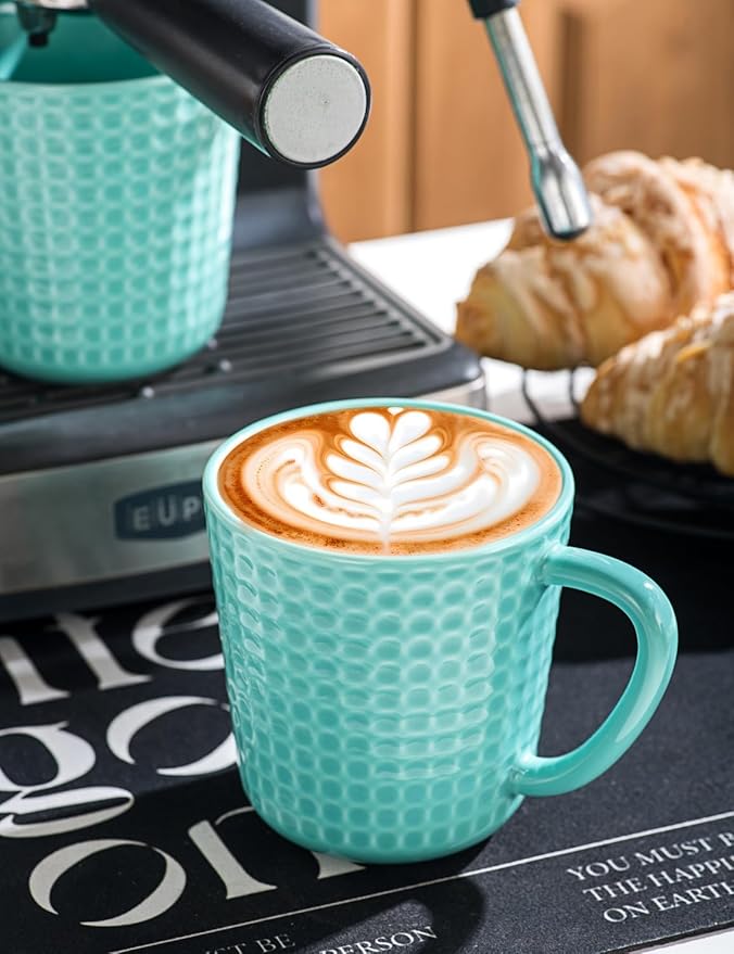 Turquoise waffle-embossed ceramic latte mug with curved handle, filled with foamy coffee