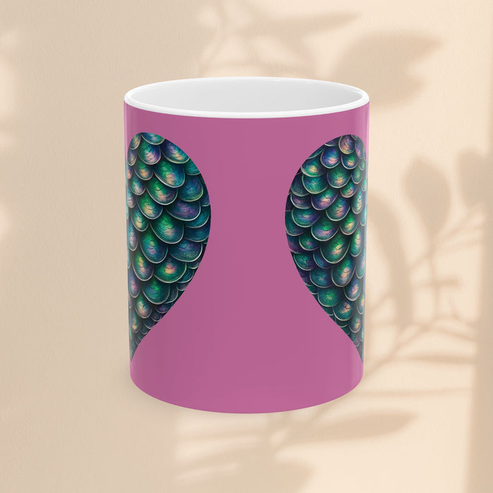 White ceramic mug with purple center and green mermaid scale wings, no handle visible