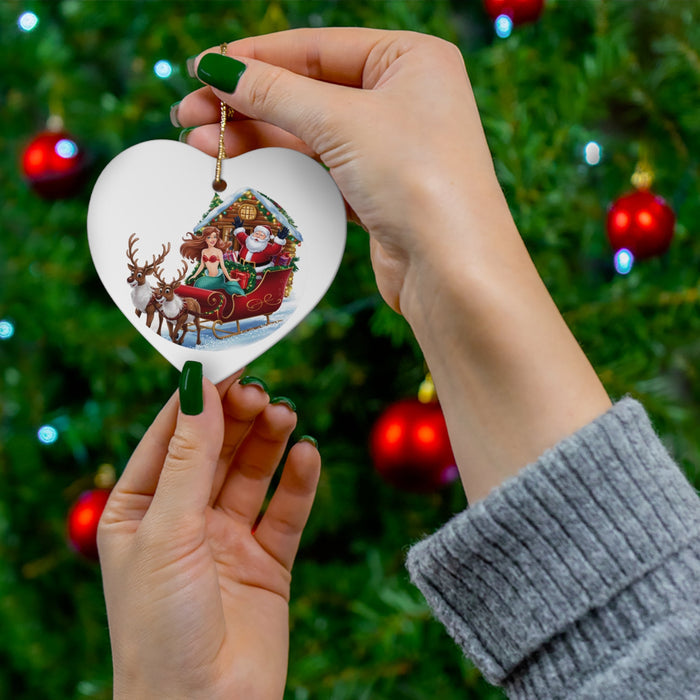 Round ceramic mermaid-and-Santa ornament held on a gold string above green Christmas tree