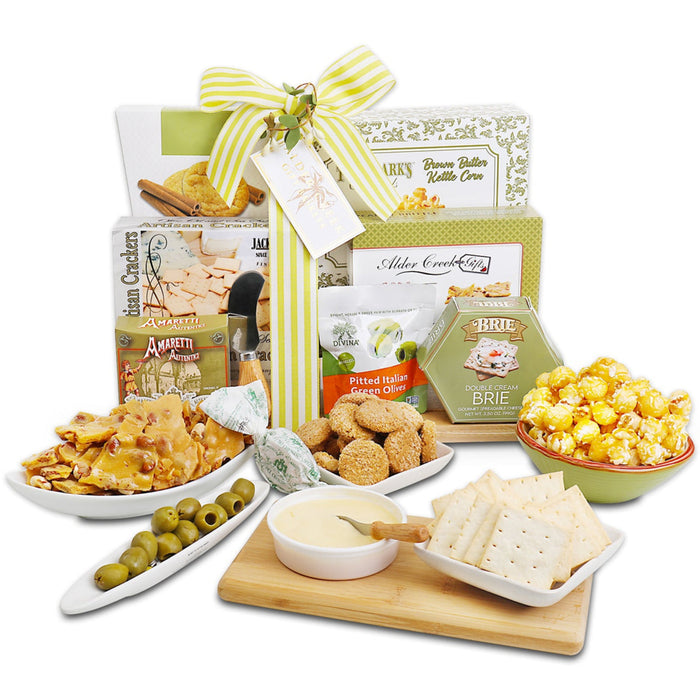 Charcuterie gift set on wooden cutting board with crackers, olives, brie, and snacks