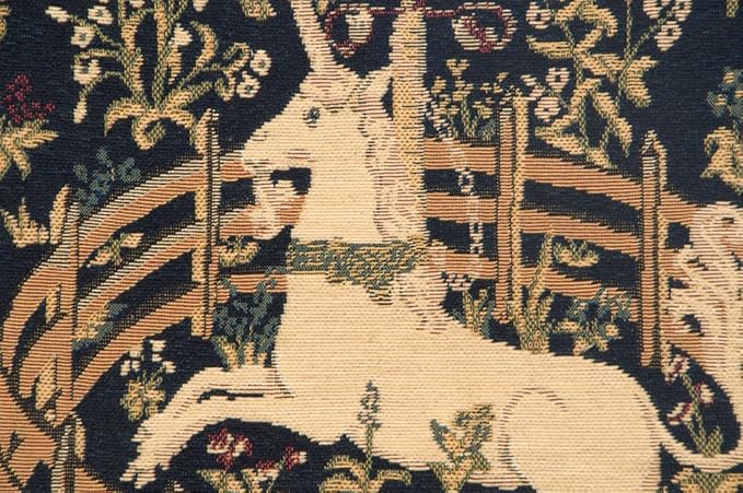 Close-up woven pillow cover: tan unicorn figure in navy floral tapestry