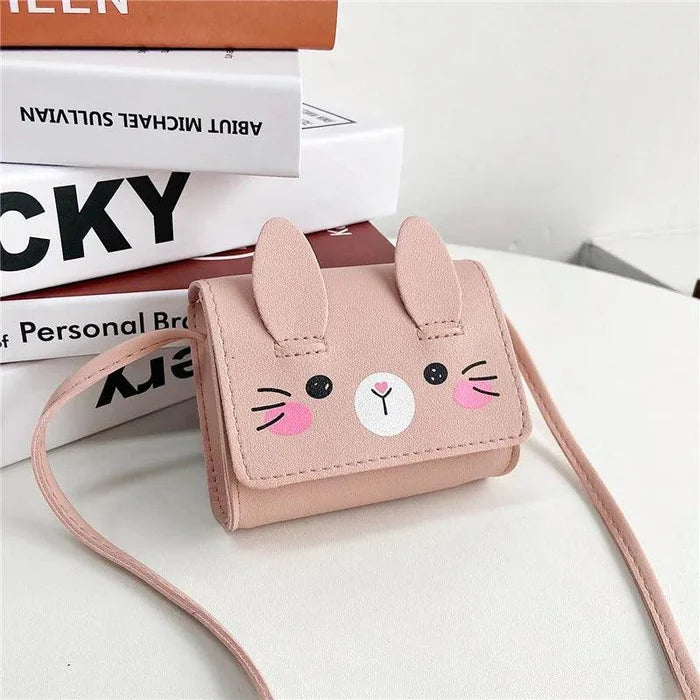 Blush pink bunny crossbody bag with stitched face, flap ears, and shoulder strap