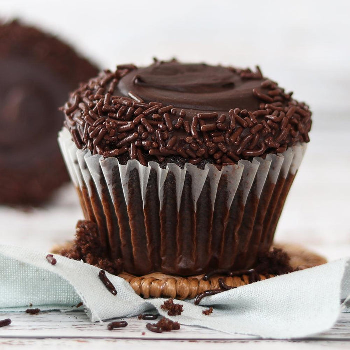 Chocolate cupcake with dark frosting and chocolate sprinkles in a paper liner