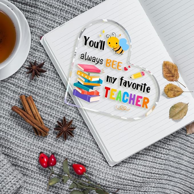 Clear acrylic heart teacher gift with bee graphic and 'favorite TEACHER' text on notebook.