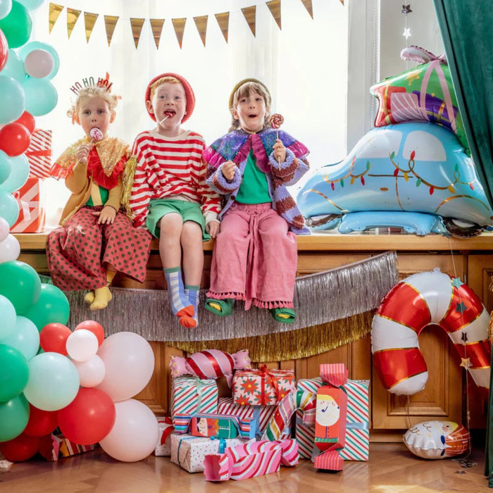 Kids sitting near party balloons with a light blue car balloon on the right