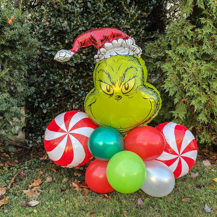 Christmas Grinch balloon bouquet with green face, red-and-white peppermint balloons, and red cap