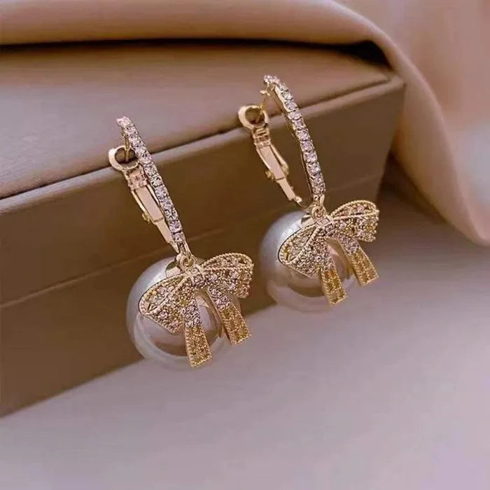 Red ornament drop earrings with gold-tone bows, rhinestone ribbons, and dangling red balls